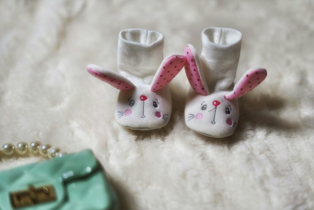 a pair of white socks with pink ears and a green purse
